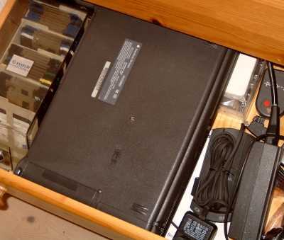laptop on its back in a drawer full of junk